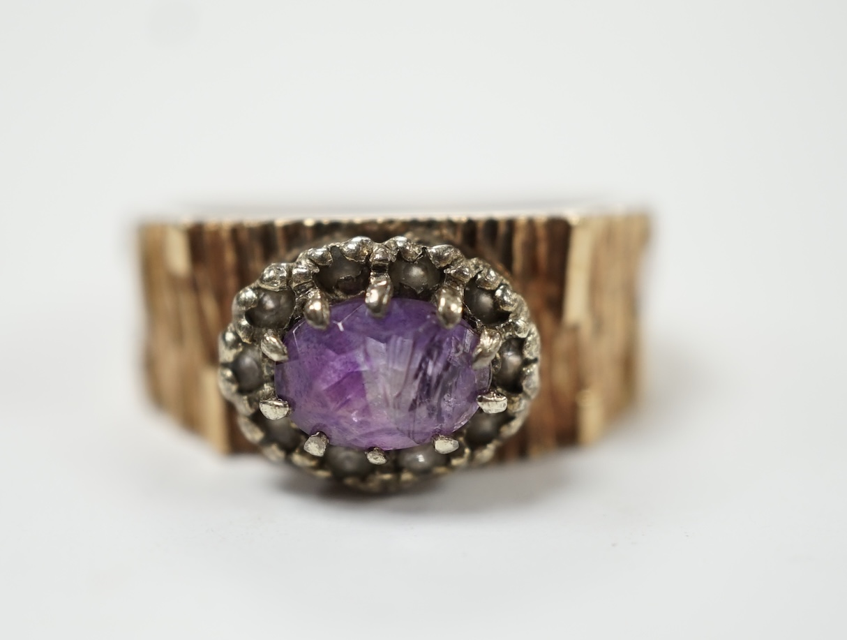 A textured yellow metal, amethyst and simulated diamond set oval cluster ring, size M, gross weight 4.4 grams. Fair condition